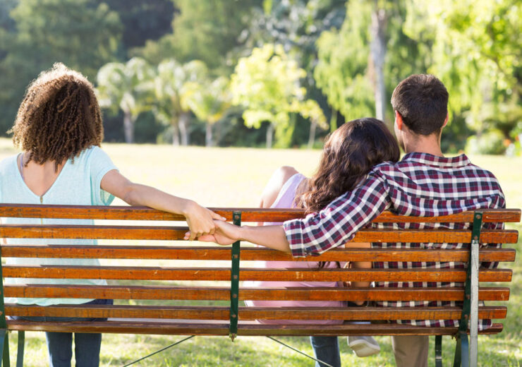 Lonely woman sitting with couple in park